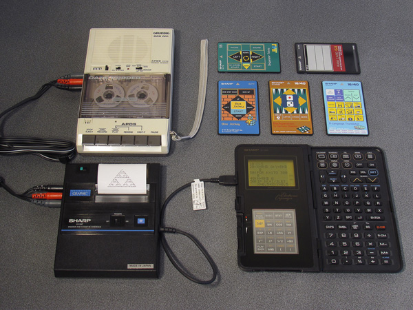 Photo of a Sharp IQ-7000 organiser connected to a CE-50P printer and cassette interface, which is in turn connected to a cassette recorder.